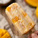 Creamy mango coconut popsicles served on a colorful plate