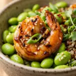 Delicious sesame ginger garlic shrimp served in a bowl with edamame and vegetables.