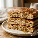 Fluffy banana pancakes stacked on a plate with fresh bananas and syrup