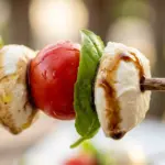 Caprese-style fruit skewers with tomatoes, mozzarella, and basil on a platter