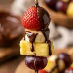 Chocolate-drizzled fruit skewers with fresh berries and pineapple