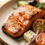 Crispy potatoes served with grilled salmon and a vibrant Greek salad.
