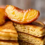 Delicious homemade peach cobbler pancakes topped with fresh peaches and syrup.