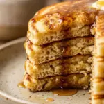 Stack of fluffy pancakes topped with syrup and berries
