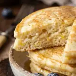 Stack of fluffy Lemon Ricotta Pancakes with syrup and lemon zest