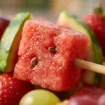 Colorful watermelon tajin fruit skewers served on a platter.
